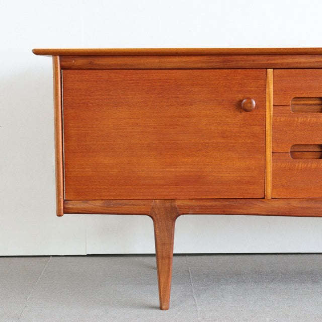 Mid-century British vintage teak sideboard by Younger with rich wood grain, round cabinet knob, and tapered legs.