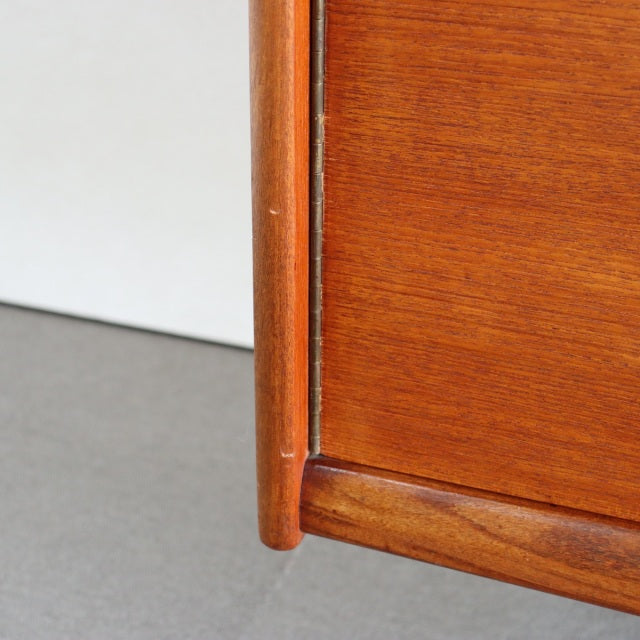 Close-up of vintage teak sideboard corner showcasing smooth wood grain and rounded mid-century British design legs.