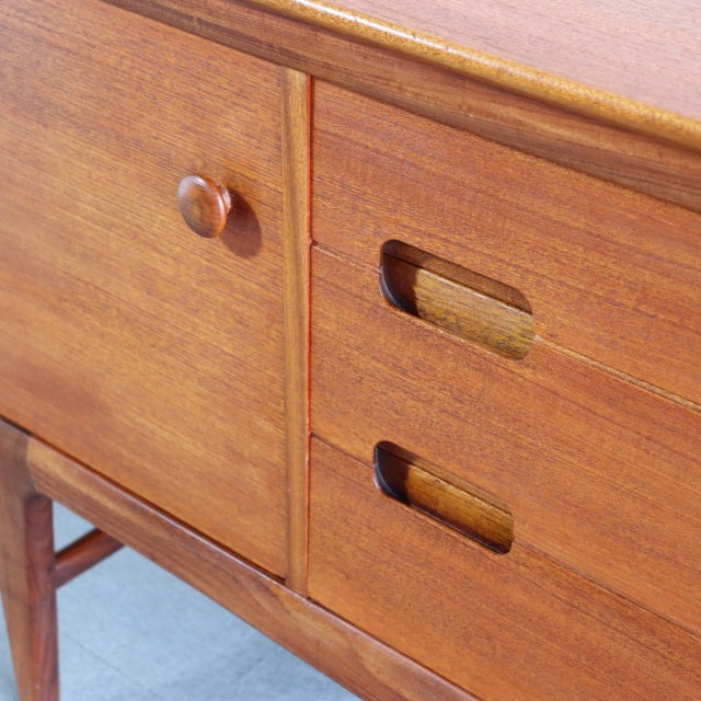 Mid-century vintage teak sideboard by YOUNGER with smooth wood grain, rounded knobs, and recessed drawer handles, British.