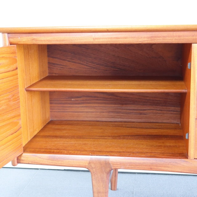 Mid-century vintage teak sideboard interior with rich wood grain, adjustable shelf, and British design legs.