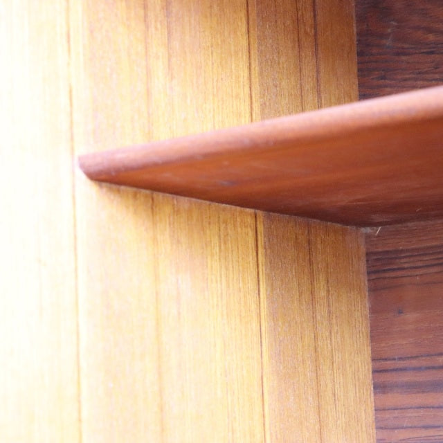 Mid-century British vintage teak sideboard corner with warm wood grain and smooth rounded edge.
