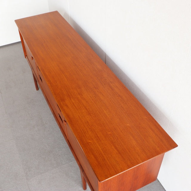 Vintage teak sideboard by Younger with smooth wood grain, mid-century British design, slender legs, and clean lines.
