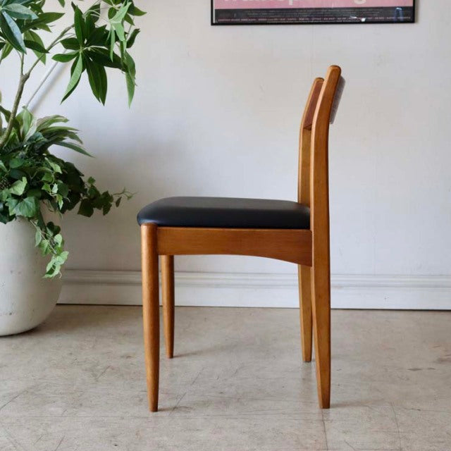 Vintage teak dining chair with black cushioned seat, slim tapered legs, and mid-century British-Denmark design.