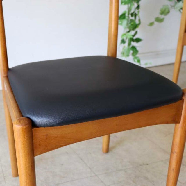 Vintage mid-century teak dining chair with smooth black leather seat, rounded legs, and visible wood grain from British.