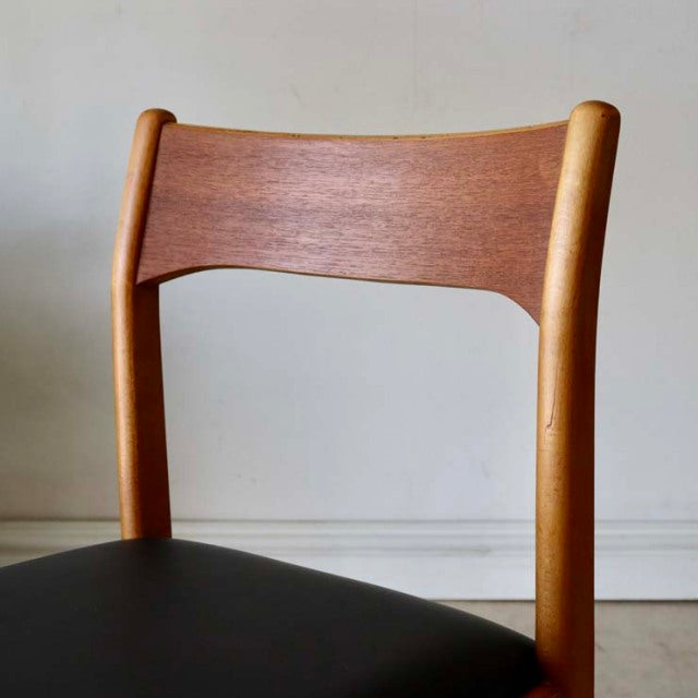 Mid-century British teak dining chair with curved wood grain backrest and black upholstered seat.
