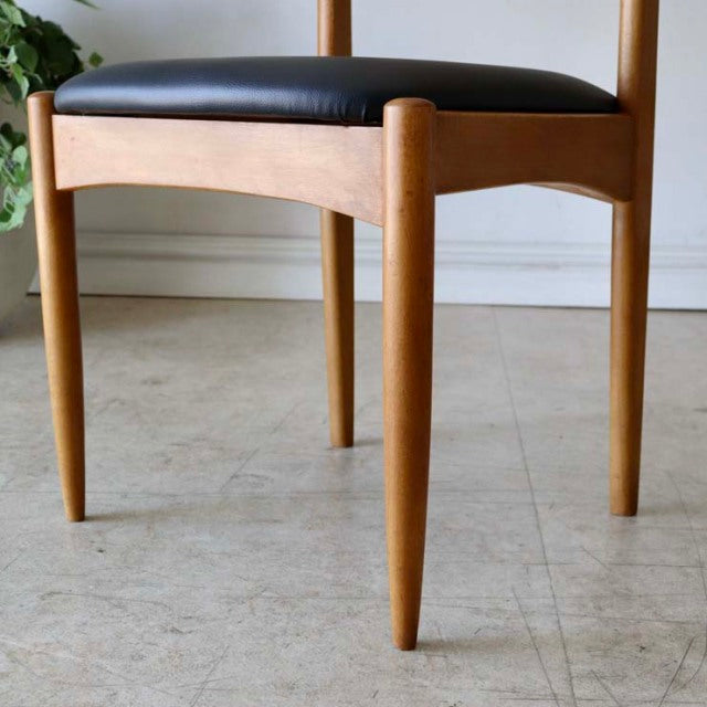 Vintage teak dining chair with black leather seat, slender tapered legs, classic British mid-century Danish design, smooth.