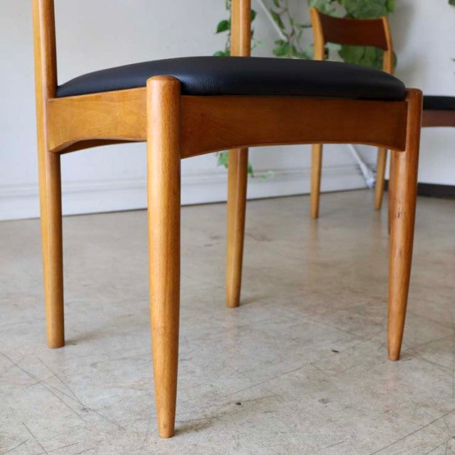 Vintage teak dining chair with tapered legs, black cushioned seat, British mid-century Danish design, smooth wood grain.