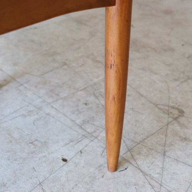 Close-up of vintage teak dining chair leg showing smooth tapered wood grain in mid-century British design from Denmark with.