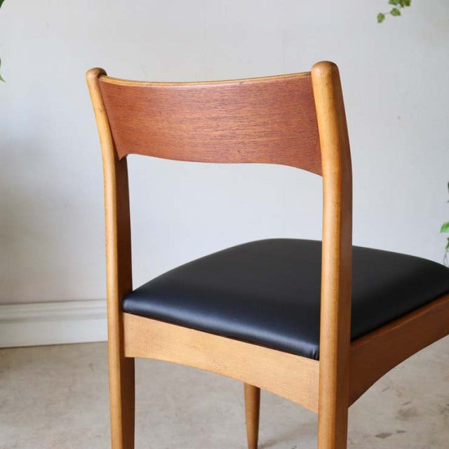 Vintage teak mid-century dining chair with smooth wood grain, curved backrest, and black leather seat from Denmark.