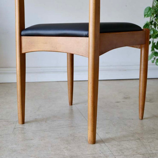Mid-century British vintage teak dining chair with smooth wood grain and black upholstered seat.