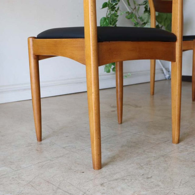 Vintage teak dining chair with tapered legs and black cushioned seat, mid-century British-Denmark style.