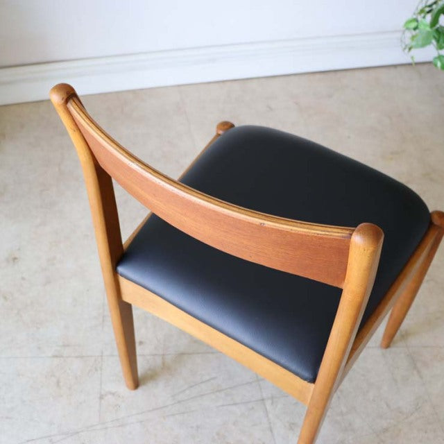 Vintage teak dining chair with smooth wood grain, gently curved backrest, and black seat cushion, reflecting British.