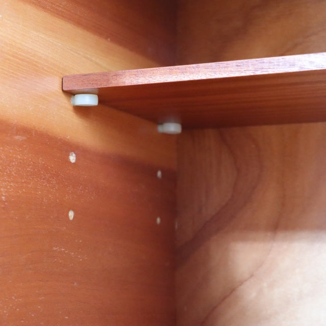 Close-up of teak wood interior shelf with visible grain and small white plastic shelf supports in mid-century British.
