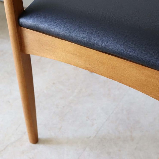 Mid-century British vintage teak dining chair with smooth black leather seat and tapered legs.