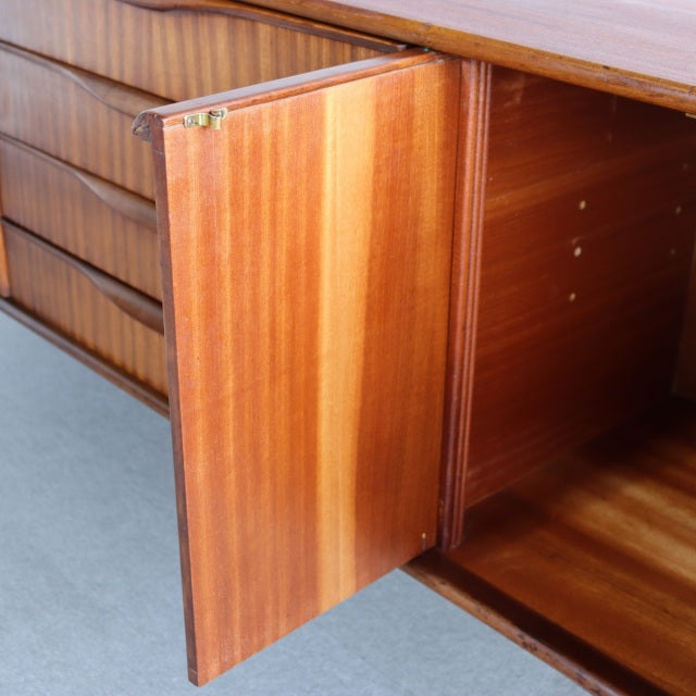 Vintage British mid-century teak sideboard by Elliotts of Newbury with visible wood grain and open cabinet door showing.