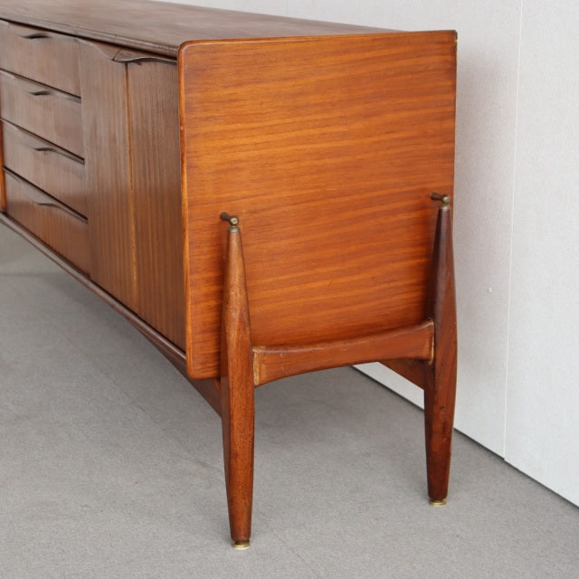 Mid-century British mid-century teak sideboard by Elliotts of Newbury with rich wood grain and tapered legs with brass caps.
