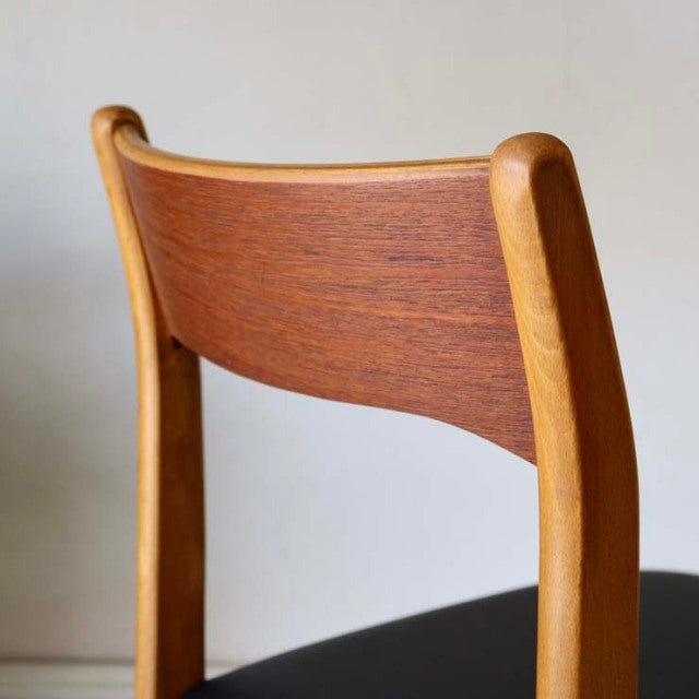 Mid-century British vintage teak dining chair with curved wood grain backrest and black cushioned seat.