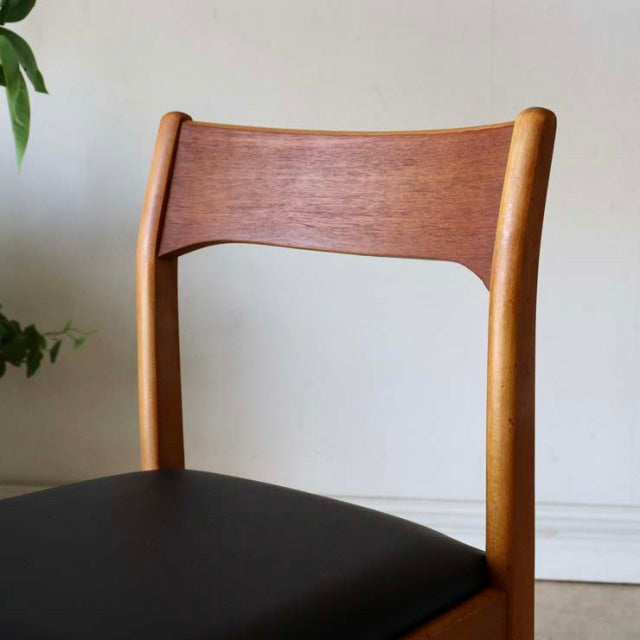 Vintage teak dining chair with sleek curved backrest, black upholstered seat, mid-century British-Denmark design, visible.