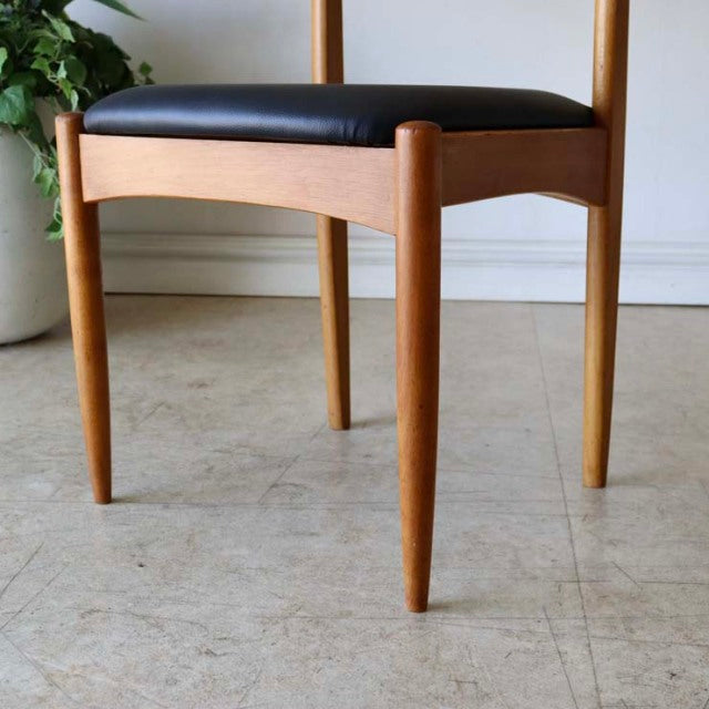 Vintage mid-century teak dining chair with black upholstered seat, tapered legs, and smooth wood grain from British-Denmark.