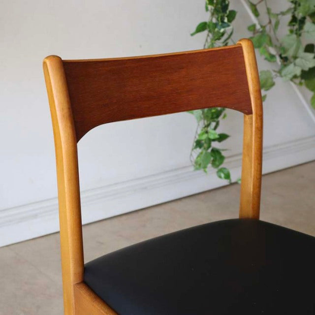 Mid-century British vintage teak dining chair with curved backrest and black leather seat, sleek wooden legs, and visible.