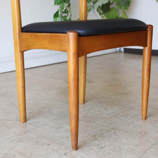 Vintage teak dining chair featuring tapered mid-century British legs and a smooth black seat, showcasing warm wood grain and .