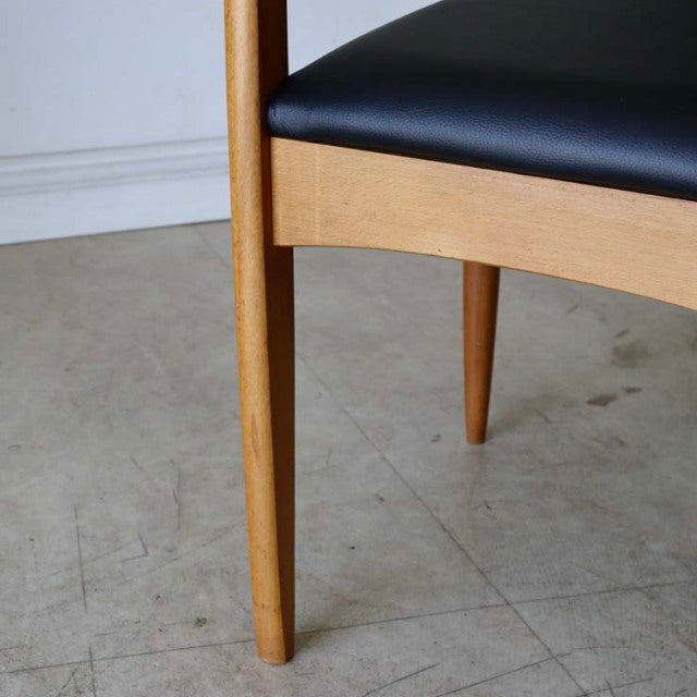 Mid-century British vintage teak dining chair with black leather seat, sleek tapered legs, and smooth wood grain.