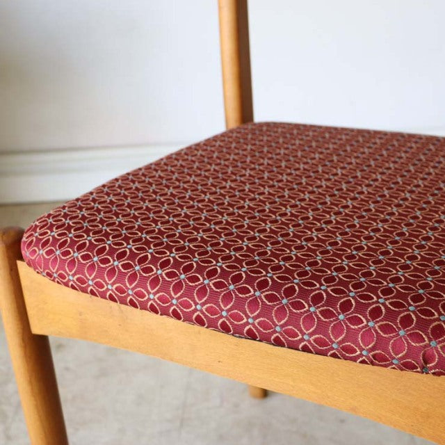Mid-century vintage teak dining chair with Danish-inspired frame and red floral patterned seat upholstery.