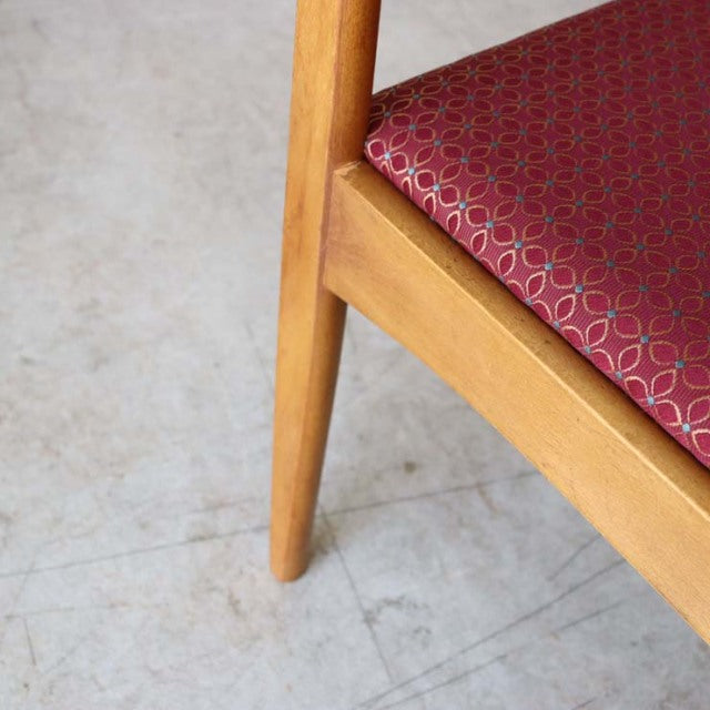 Mid-century British vintage teak dining chair leg with smooth wood grain and tapered design, red floral seat upholstery with .