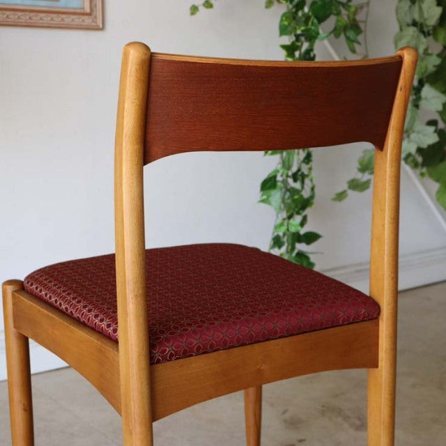 Vintage mid-century teak dining chair from British-Denmark design featuring rich wood grain and textured deep red.