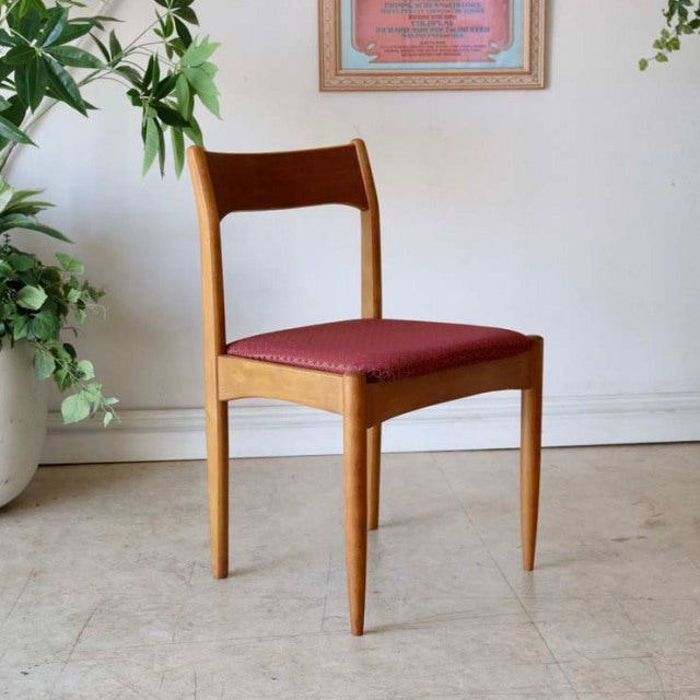 Vintage British mid-century teak dining chair from Denmark with smooth wood grain and red upholstered flower seat.