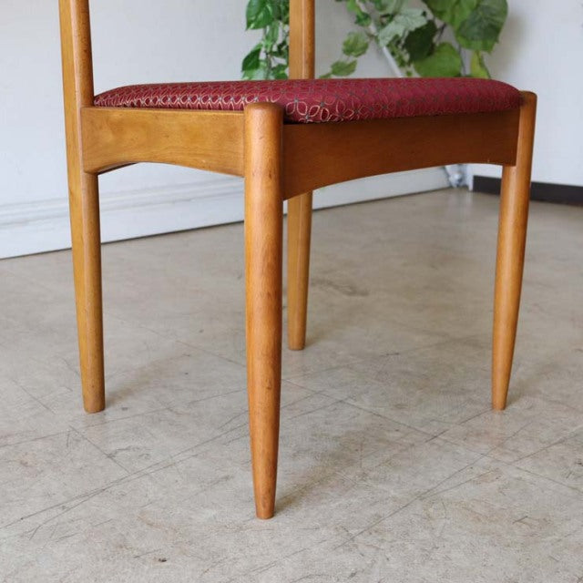 Vintage teak dining chair with tapered legs and rich wood grain, featuring a deep red flower-patterned seat, classic British .
