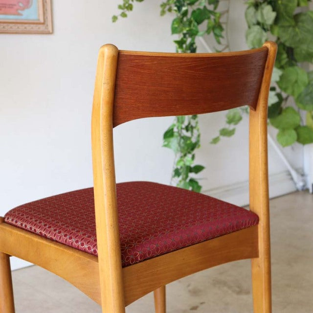 Mid-century British vintage teak dining chair with curved backrest and textured red floral seat cushion.