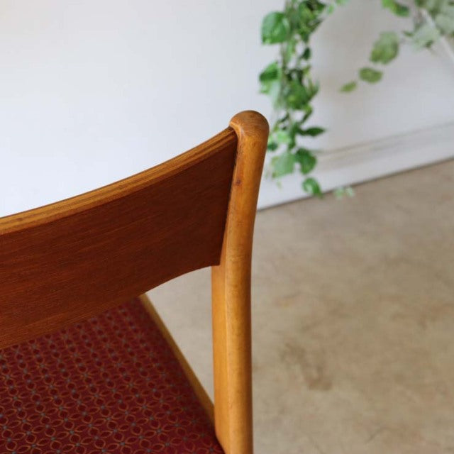 Mid-century British vintage teak dining chair with curved smooth frame and red floral patterned seat, Danish design influence.