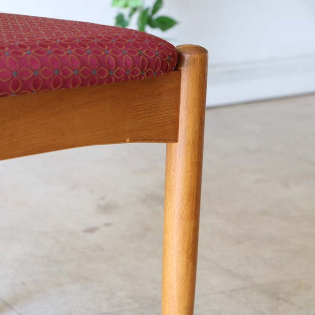 Mid-century British vintage teak dining chair leg with visible wood grain and red floral upholstered seat from Denmark.