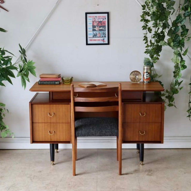 Vintage teak G-Plan mid-century British desk with wood grain, brass handles, tapered black legs, and matching chair with.