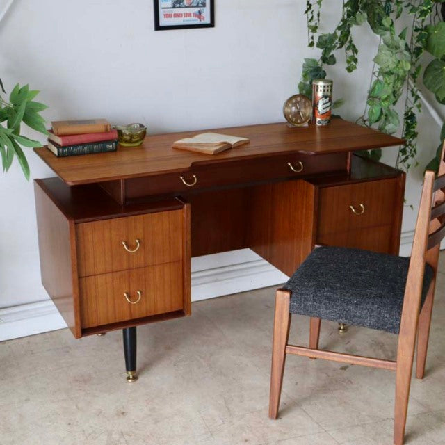Vintage British G-Plan teak desk with mid-century Denmark design, brass handles, sleek tapered legs, and rich wood grain.