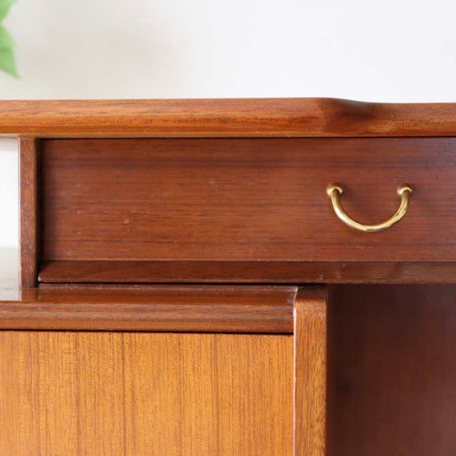 Vintage teak G-Plan desk drawer and cabinet section showing rich wood grain and brass handle, mid-century British design.