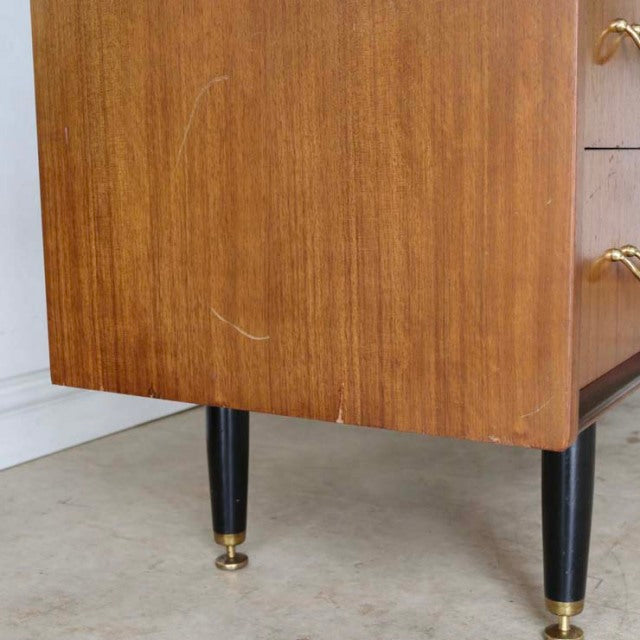 Vintage teak G-Plan desk side showing wood grain, black tapered legs with brass caps, British mid-century design.