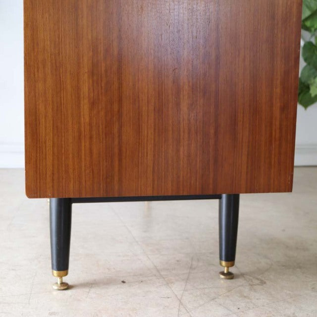 Vintage teak wood desk leg from British mid-century G-PLAN, tapered black legs with brass caps, smooth wood grain.