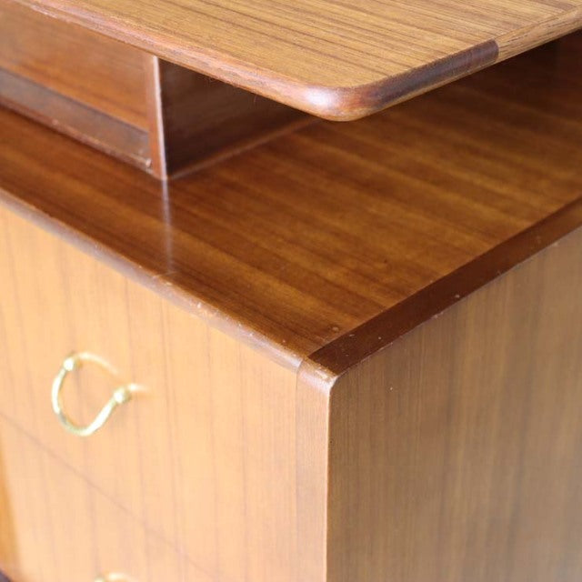 Vintage teak G-Plan desk corner showing smooth wood grain, curved edge, and brass drawer handle in British mid-century.