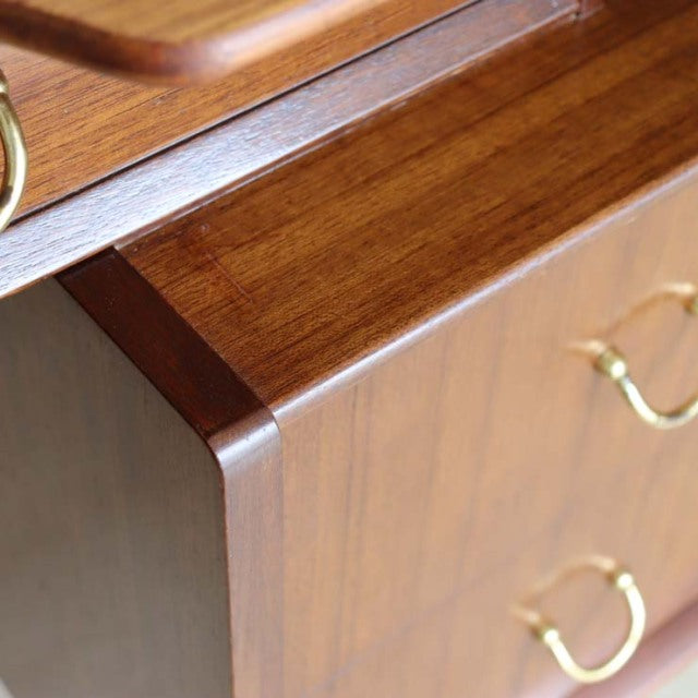 Vintage mid-century British G-PLAN teak desk corner with rich wood grain and brass handles.