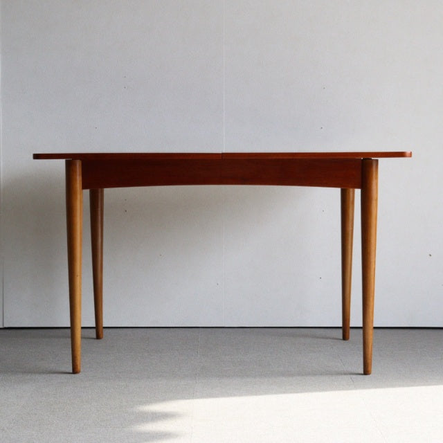 Vintage teak dining table with sleek tapered legs, British mid-century design from Denmark, showcasing rich wood grain and.