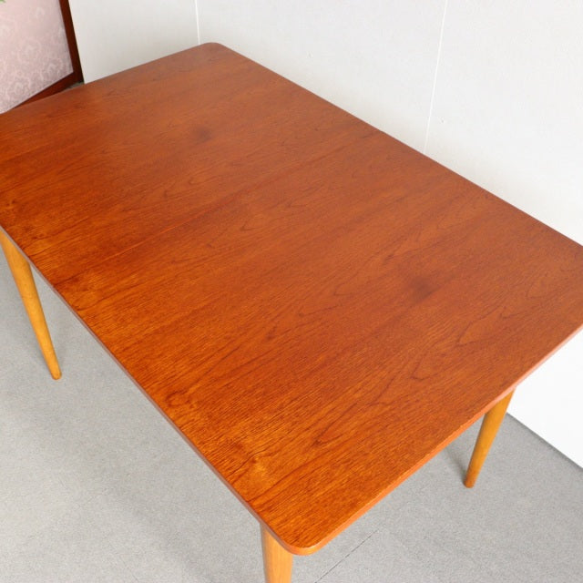 Vintage British mid-century teak dining table with smooth wood grain and tapered legs from Denmark.