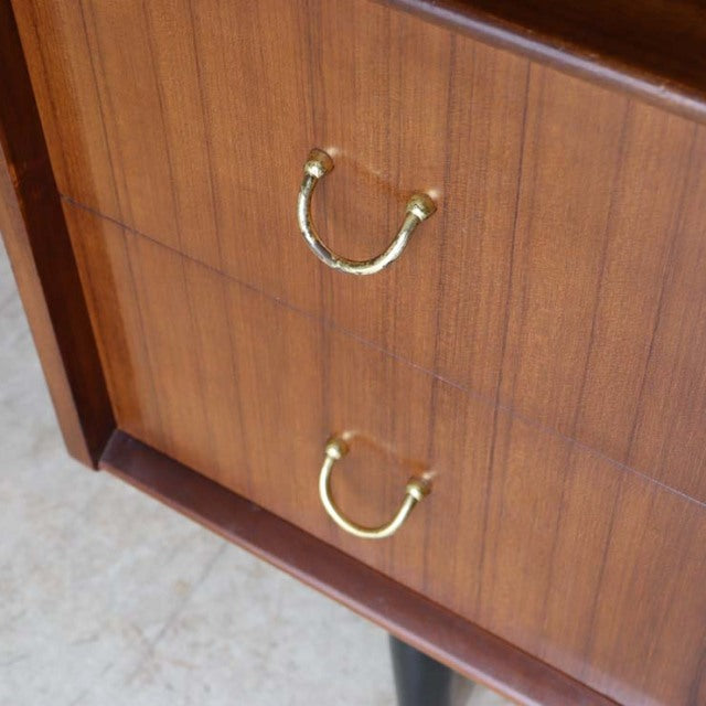 Close-up of vintage teak G-PLAN desk drawers with brass arch handles and rich wood grain, British mid-century design.