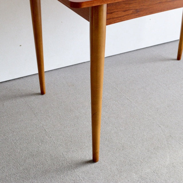 Mid-century British vintage teak dining table leg with tapered cylindrical design and smooth grain finish on light carpet.