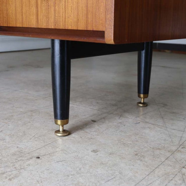Close-up of black tapered legs with brass caps on vintage teak G-PLAN desk, British mid-century Denmark design.