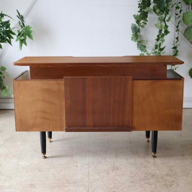 Vintage British G-Plan teak desk with mid-century Danish design, showcasing rich wood grain, angled black legs with brass.