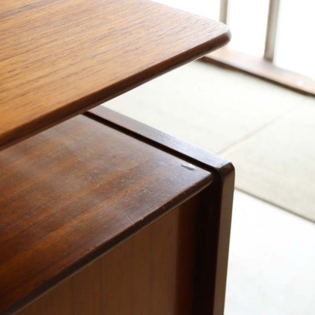 Close-up of vintage teak G-PLAN desk corner showing smooth wood grain and curved mid-century British design details.