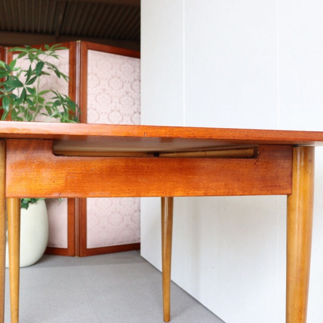 Mid-century vintage teak dining table with smooth wood grain, British-Denmark design, and slender tapered legs.