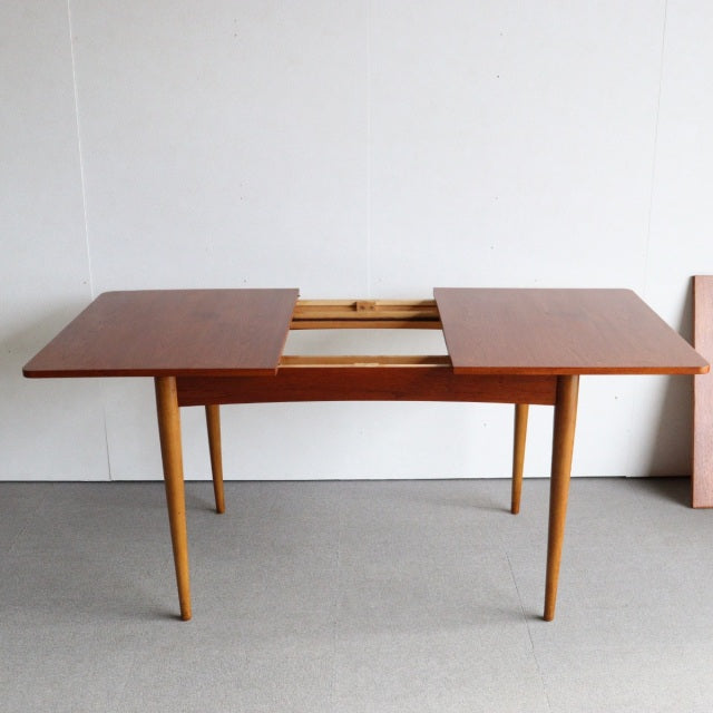 Mid-century vintage teak dining table with sleek British design, smooth wood grain, and tapered legs from Denmark style.